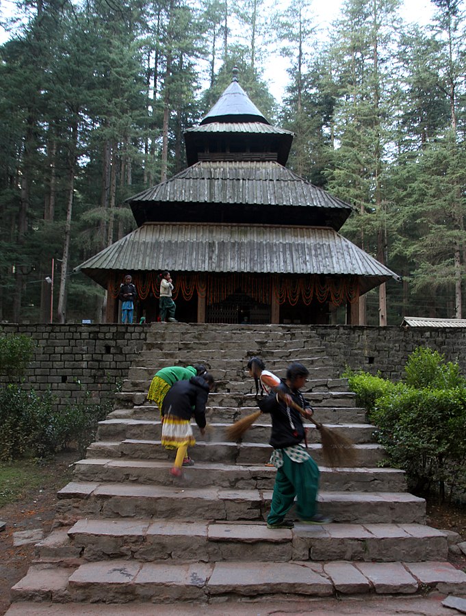 A group of people on stairs in front of Hidimba Devi Temple